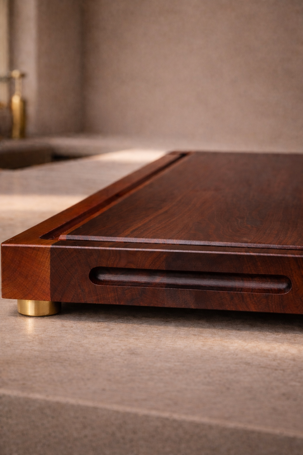 Close detail of The Harvest cutting board with elevated gold feet and refined edge profile