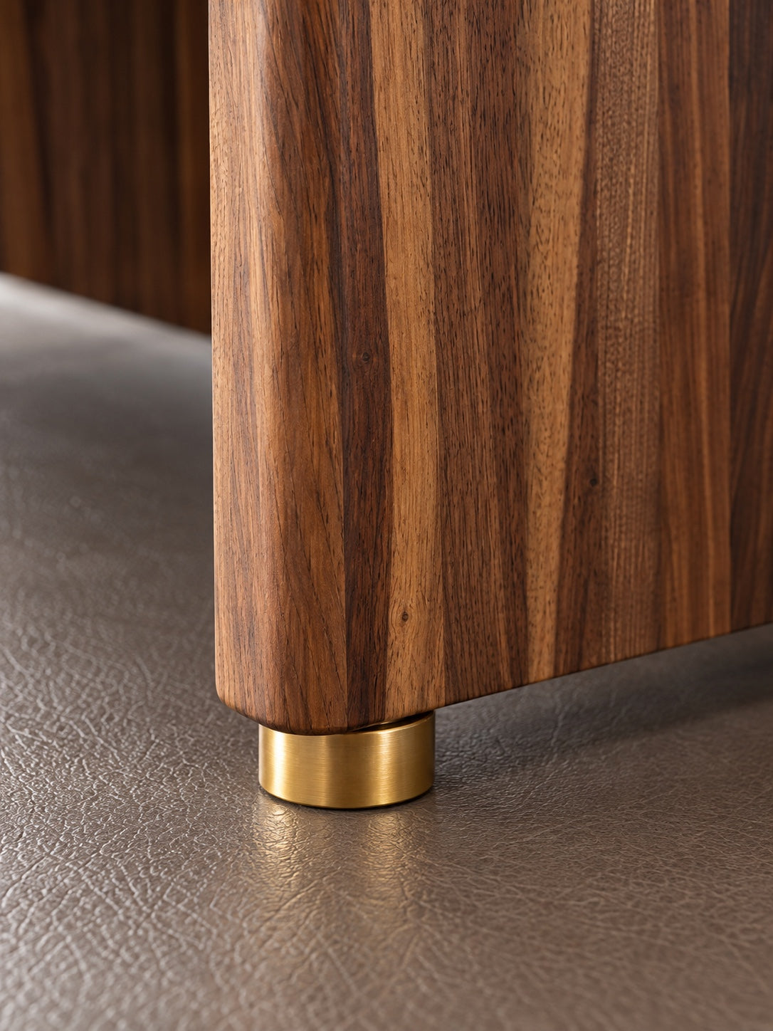 Close detail of The Archive's brass foot and solid walnut side panel