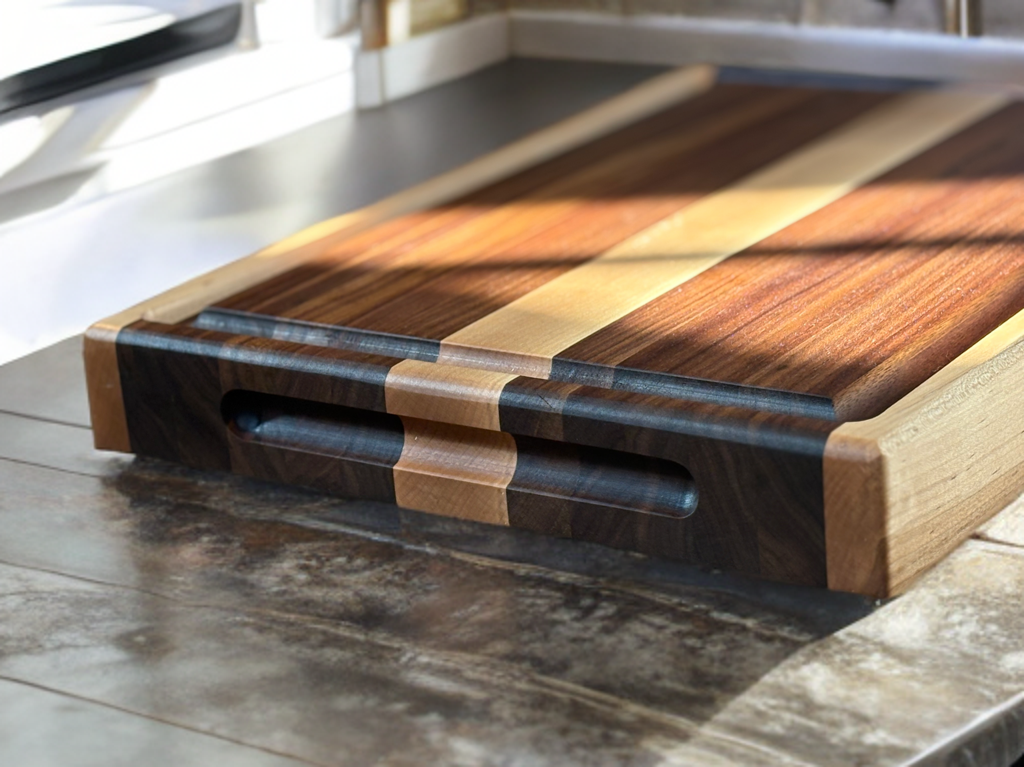 Side angle of The Ridge cutting board on kitchen counter showing recessed handles and thick profile.
